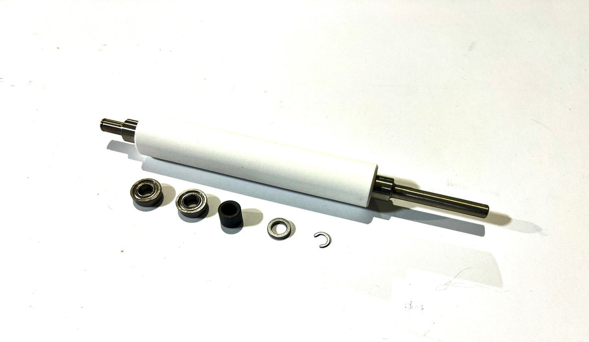 A white ZEBRA platen roller with metal shaft and several small black components placed around it, likely for installation or replacement in a thermal printer.